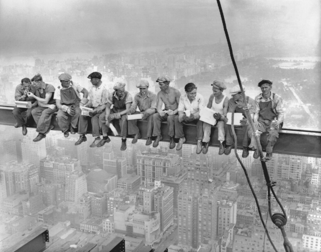Vintage photo of men eating lunch on an iron girder suspended above new york city, in violation of New York Labor Law